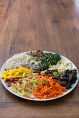 Japchae- Korean sweet potato noodle salad with meat and vegetables. Oak table. Copy space. 