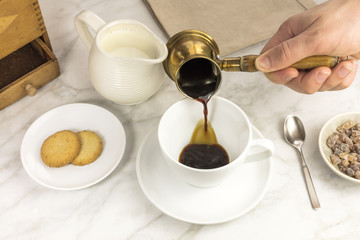Coffee poured into cup, with milk jar and cane sugar