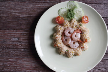 Shrimp fried rice dish in white on a wooden floor.