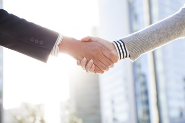 Men and women are shaking hands in front of the office building