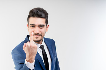 Young attractive man in a blue suit showing middle finger on a gray background. Isolated