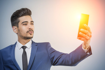 Young attractive man in a blue suit looking at a glowing the phone's screen
