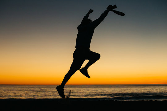 Silhouette of a happy man athlete celebrating winning success at sunset or sunrise elated with arms above his head in celebration reached his goal during hiking travel trek.
