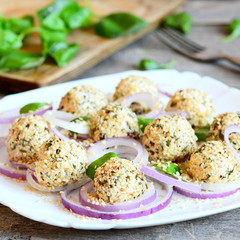 Holiday cheese balls on a plate. Cheese balls with dried herbs and roasted sesame seeds served with raw onion rings and fresh basil leaves. Vintage style. Closeup