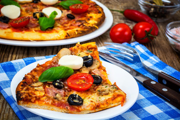 Italian pizza with ham, cheese, mushrooms, tomatoes and mozzarel