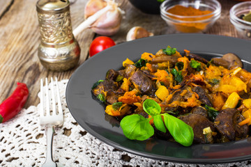 Fototapeta na wymiar Roasted vegetables with pumpkin and mushrooms on a black plate