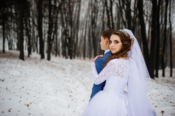 Young stylish wedding couple at forest on winter day. Loving new