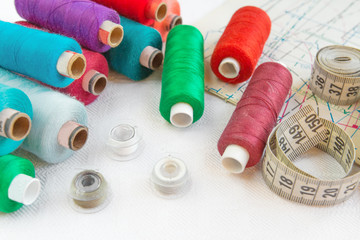 Fototapeta na wymiar Accessories for sewing.Multi-colored thread,scissors,measuring tape,bobbins,pattern.