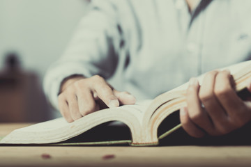 Young man is sitting on table and reading a book