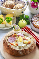 The sour rye soup inside loaf of bread. Easter breakfast table.