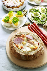 The sour rye soup inside loaf of bread. Easter breakfast table.
