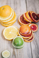 Delicious fresh fruit rainbow: orange oranges, blood oranges and green limes on the wooden table background