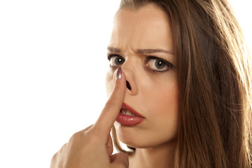 young unhappy woman raised her nose on white background