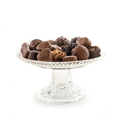 Chocolate praline assortment on an elegant glass serving plate isolated on white