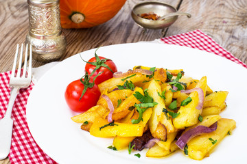 Potato wedges, onion and greens on white plate