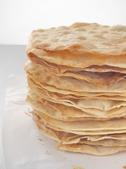 Cooking process. Preparing multi-layered cake. Crusts for homemade mille feuille. Big pile of fresh pancakes. Close up. Side view.