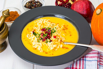 Vegetable cream soup with noodles, curry and pomegranate