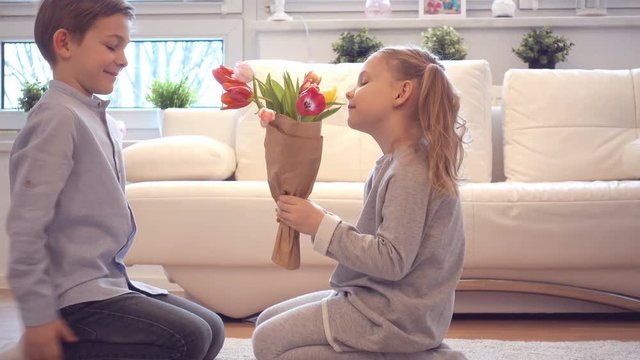 Cute child boy present bouquet of flowers to pretty little girl for Valentines day
