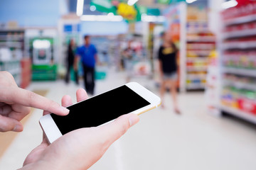 Woman hold mobile smartphone while shopping in supermarket