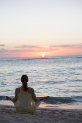 Fototapeta na wymiar femme en position de yoga au crépuscule sur la plage