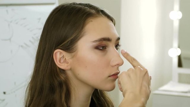 Professional female make-up artist applying eyeshadow on the eyelid on the girl's face. HD