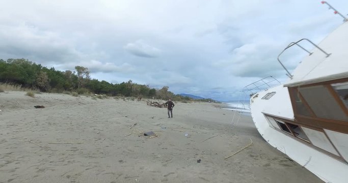 Ragazzo che passeggia sulla spiaggia scopre una valigetta vicino a una barca arenata