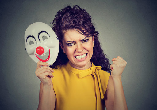 Angry screaming woman taking off clown mask expressing happiness