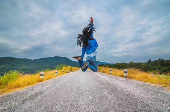 Beautiful girl jumping on the rural road