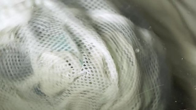 close up view of dirty cloths circular motion in washing machine