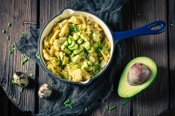 Healthy scrambled eggs with avocado for breakfast on wooden table