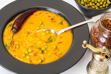 Vegetarian food: vegetable soup with green peas in black plate