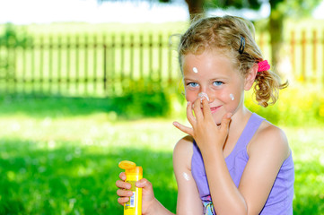 blond girl using sun cream in garden