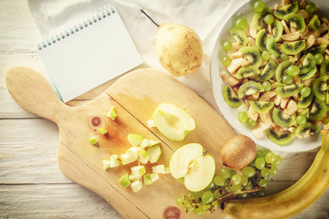 Ingredients for fruit salad. Cutting apple