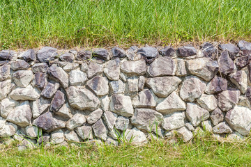 Natural style of exterior stone cement wall in green grass backg