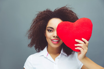 African American young happy girl holding heart shape symbol 