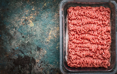 Raw minced meat in plastic box on rustic background, top view, place for text