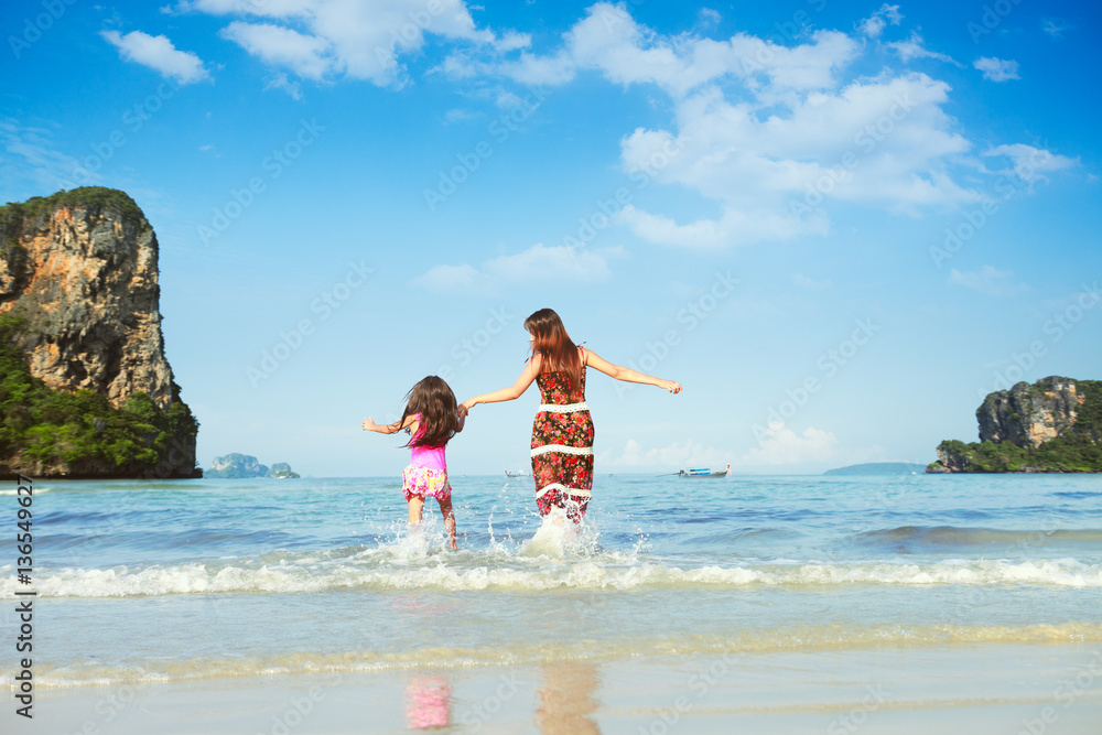 Wall mural happy mother and young daughter on the beach