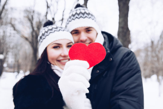 A young couple holding a red heart symbol of love.