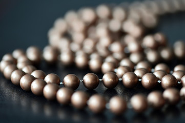 Long necklace made of brown beads on a dark background 