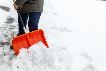 Woman with shovel cleaning snow. Winter shoveling. Removing snow after blizzard.