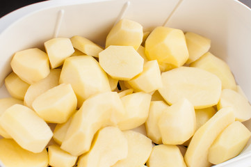 Sliced, peeled raw potatoes in a bowl