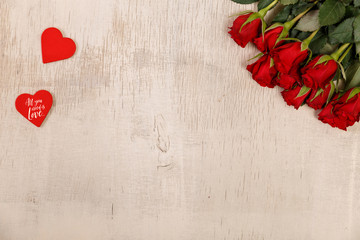 Red roses with hearts on wood background. Love design. Valentines day concept. Fresh natural flowers. All you need is love.