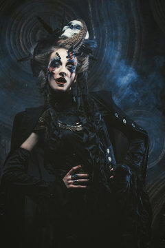 Young  woman wearing dark costume. Bright make up and smoke-  halloween theme.