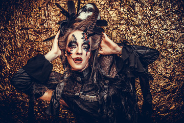 Young  woman wearing dark costume. Bright make up and smoke-  halloween theme.