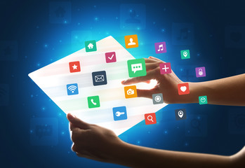Hands touching a glass-like tablet with colorful icons