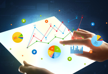 Hands touching a glass-like tablet with charts