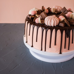 Biscuit cake with chocolate drips, marshmallows and marmalade, slice of chocolate. Sweets and food