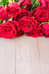 Dark Red buds of valentines day fresh roses border on gray wood with copy space