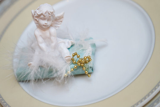 Close up photo of Festive table decoration with white plaster angel on plate.