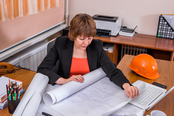 Female engineer working with a project. Checking the drawings.